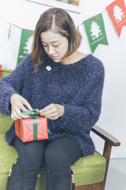 年轻女子坐在沙发上，手里拿着礼品盒图片下载