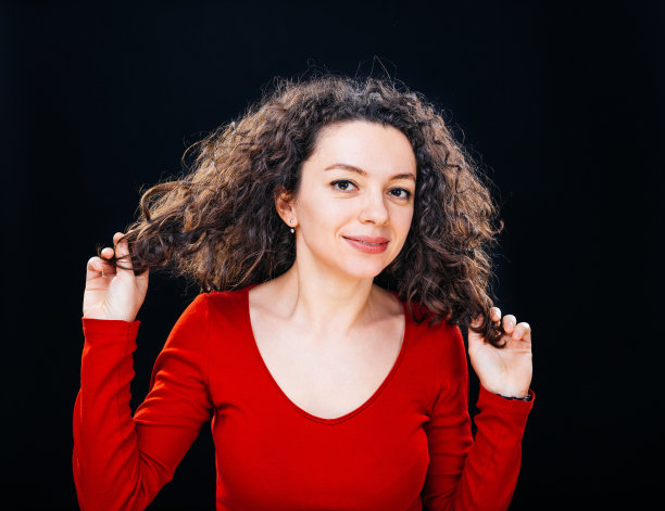 卷发女人，手放在头发上图片下载