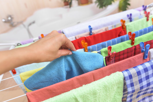 用手从烘干机中拿走衣服。图片下载