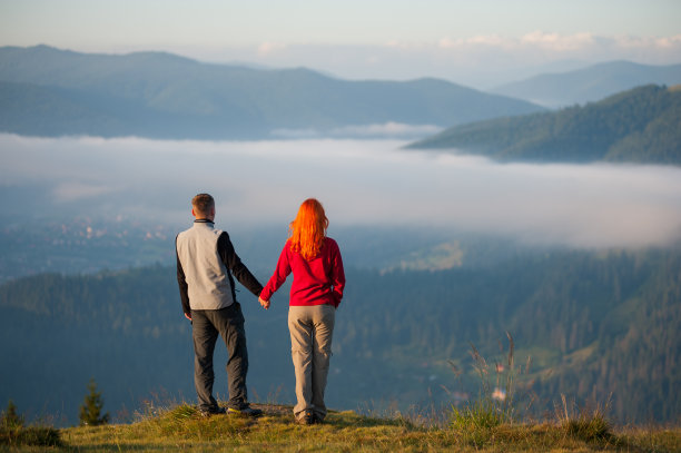 后视图浪漫的夫妇站在山上，手牵着手图片下载