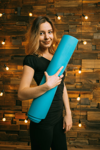 年轻迷人的女人拿着瑜伽垫图片下载