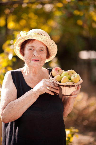 年长的女人拿着新鲜的青苹果图片下载