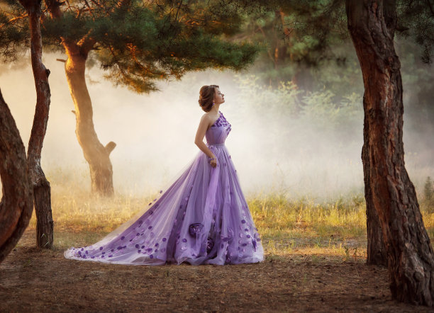 美丽的女孩穿着华丽的紫色长裙在户外散步图片下载