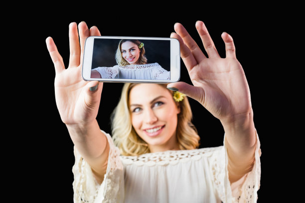 微笑的女人点击照片从手机的黑色背景图片下载