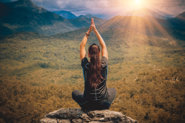 年轻女子坐在山顶莲花的姿势。图片下载