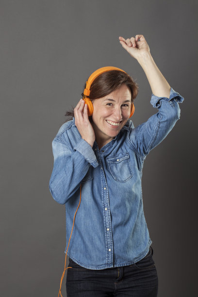 微笑的中年妇女享受跳舞和啪的音乐图片下载