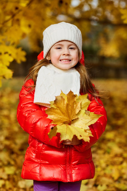 小女孩穿着鲜艳的衣服，用树叶的手微笑着图片下载