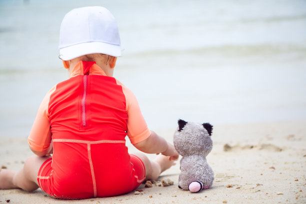 小的朋友。婴儿在海滩上玩玩具动物图片下载