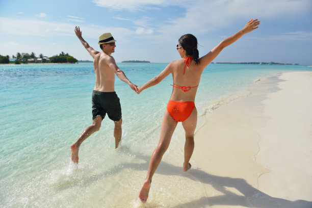 快乐的年轻夫妇在海滩上玩得开心图片下载