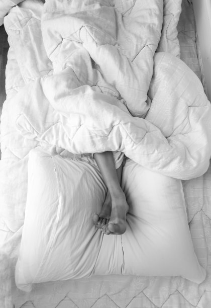 女孩脚躺在床上的枕头上的黑白照片图片下载