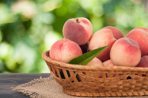 桃子装在柳条篮子里，放在木桌上模糊不清图片下载