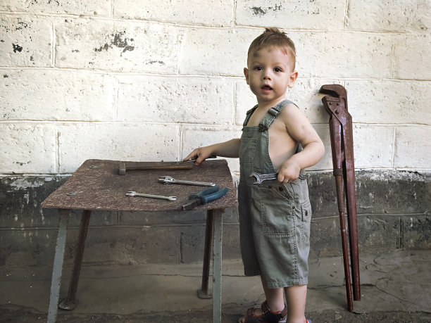 小男孩拿着扳手站在墙上图片下载