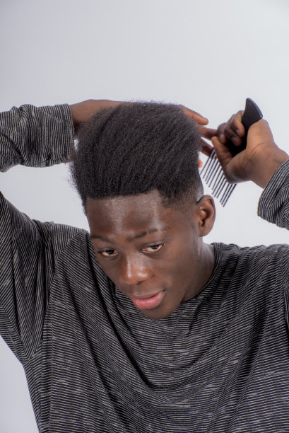 年轻的非洲男子用传统的梳子梳紧头发图片下载