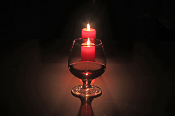 圣诞作文照片，白兰地酒杯和蜡烛在黑色的背景图片下载