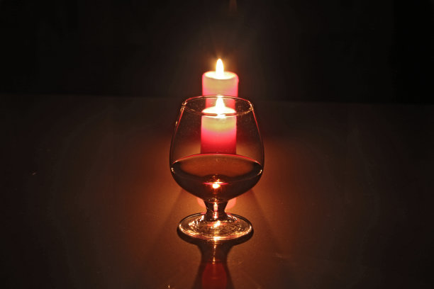 圣诞作文照片，白兰地酒杯和蜡烛在黑色的背景图片下载