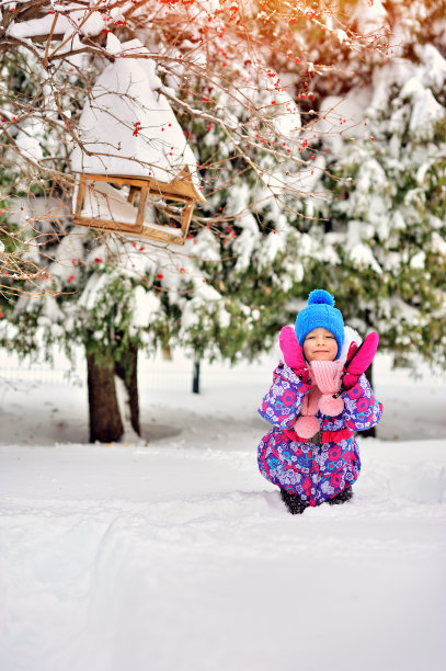 戴着粉色手套的快乐小女孩在雪地里。图片下载
