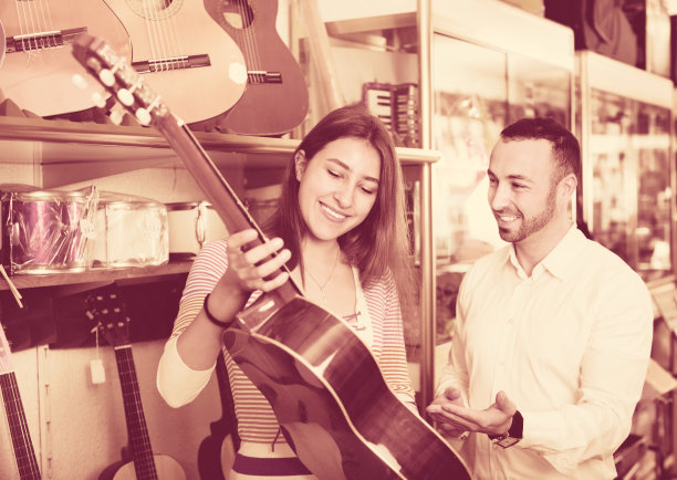 友好积极的女店员帮助男性客户选择吉他图片下载