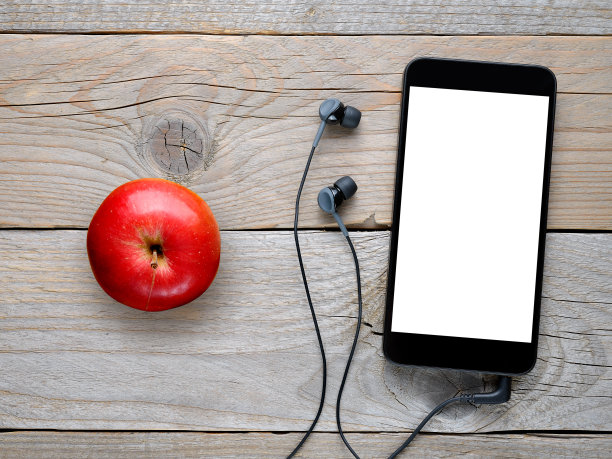 带耳机的智能手机，木桌上放着红苹果图片下载