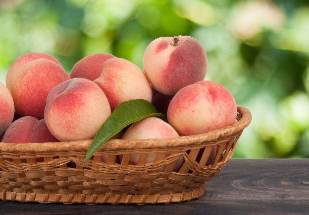 桃子装在柳条篮子里，放在木桌上模糊不清图片下载