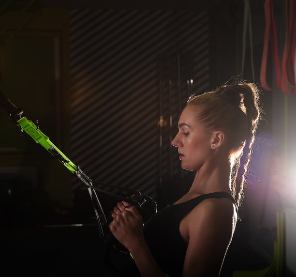 妇女做引体向上与trx健身带训练手臂图片下载