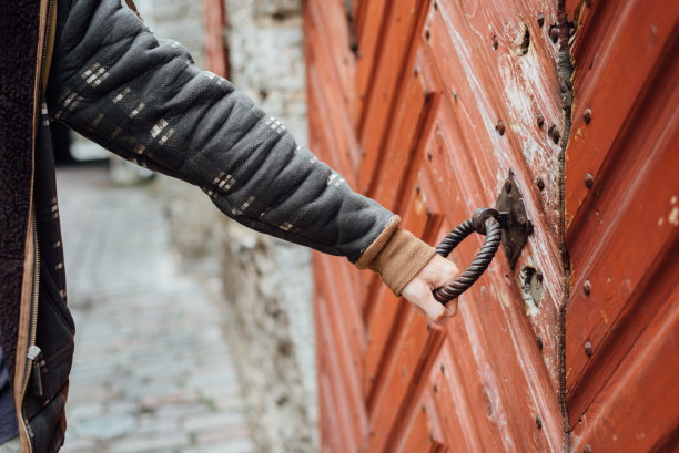 在中世纪的城镇里，男人手握着古老的门把手图片下载