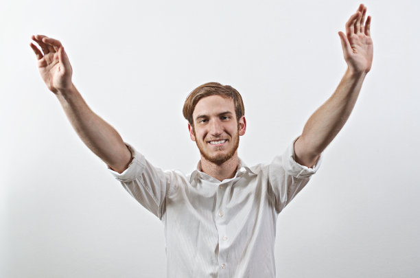 微笑快乐，快乐的年轻人在白衬衫，举起手臂图片下载
