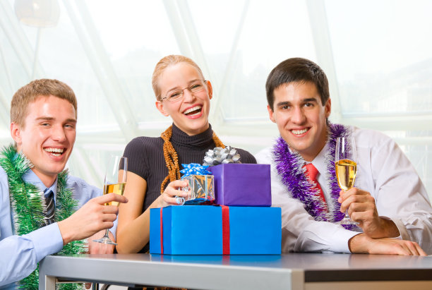 三位快乐的商人在庆祝会上拿着香槟和礼物图片下载