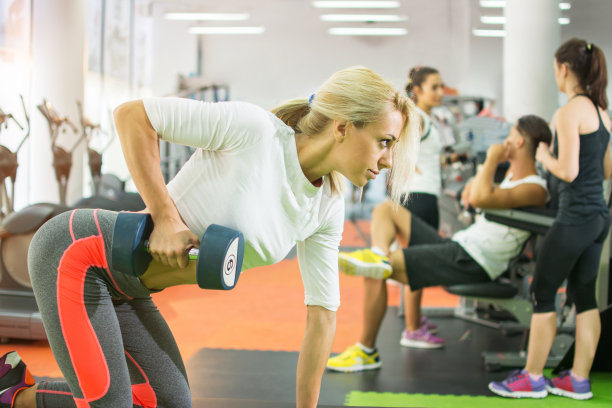 健身女孩在健身房举哑铃。图片下载