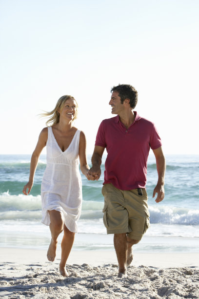 一对年轻夫妇在海滩上跑步度假图片下载