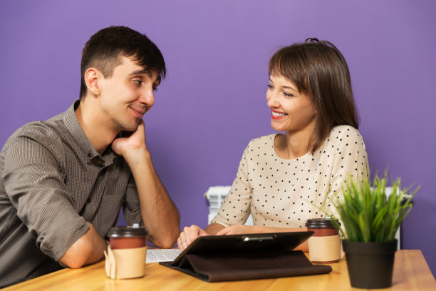 一对年轻夫妇拿着平板电脑坐在桌子旁图片下载