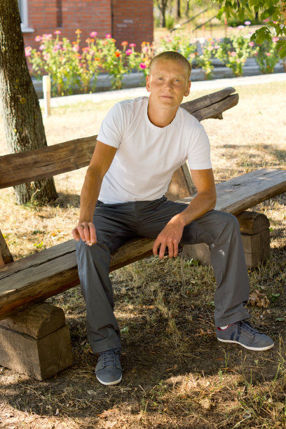 微笑的男人坐在公园的长椅上图片下载