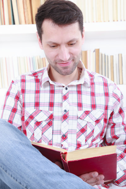 休闲男坐在沙发上看书图片下载