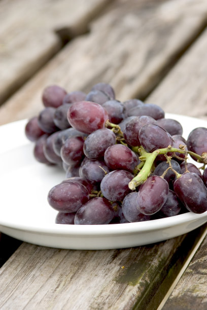 葡萄放在木桌上，白色的盘子图片下载