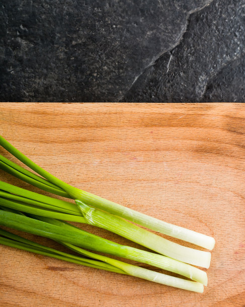 切菜板上放一束葱。素材图片