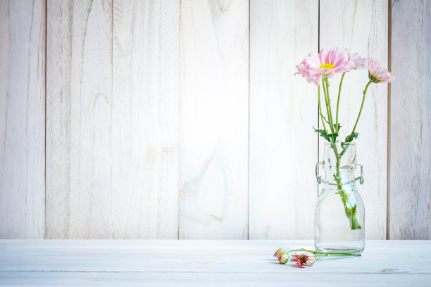一束粉红色的花插在花瓶里，插在白木上。素材图片