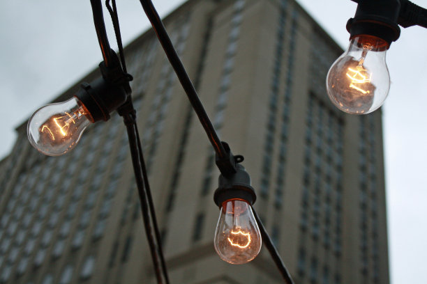 三个灯泡串在一起，以建筑为背景图片下载