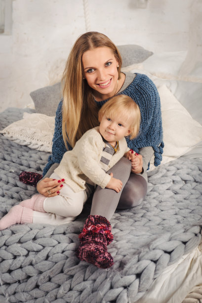 快乐的金发母亲拥抱着她的小女儿。舒适的家。图片下载