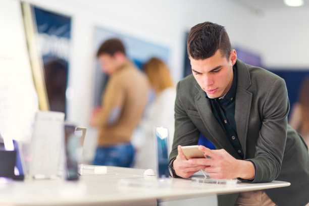 年轻人在商店里挑选智能手机，面带微笑素材图片