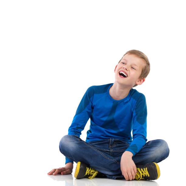 笑着的小男孩，交叉着双腿坐在地板上。图片下载