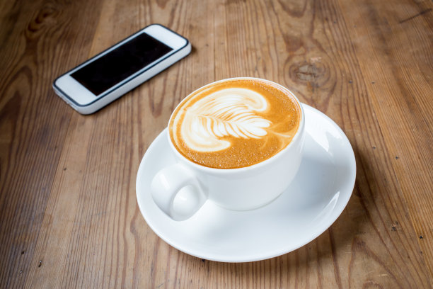 木桌上放着咖啡拿铁杯和电话图片下载