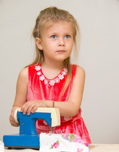 正在用玩具缝纫机缝纫的金发小女孩图片下载
