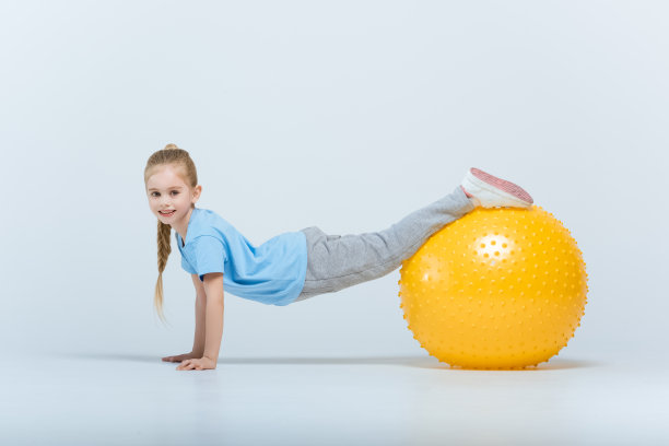 微笑运动女孩锻炼与健身球在白色素材图片
