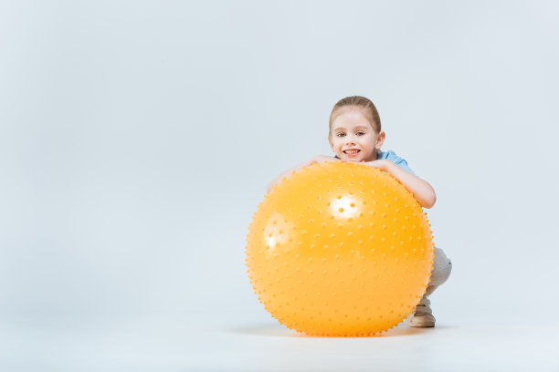 微笑的运动女孩坐在健身球附近图片下载