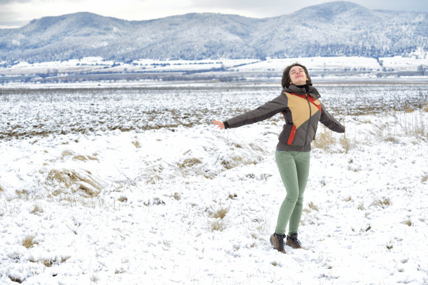幸福的女人举起双臂，身后是雪山图片下载