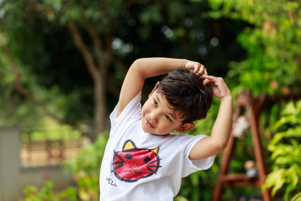 微笑的小男孩做一个爱的标志，心，绿色的花园背景。图片下载