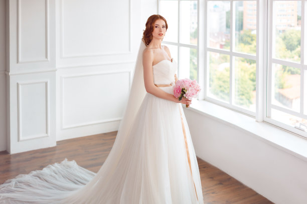 新娘身着白色婚纱，戴着长长的面纱和一束鲜花图片下载