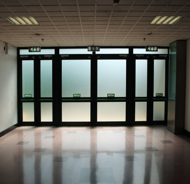 在光线昏暗的走廊里，玻璃门上方的出口标志图片下载