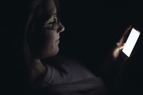 年轻女子晚上在黑暗的房间里使用手机图片下载