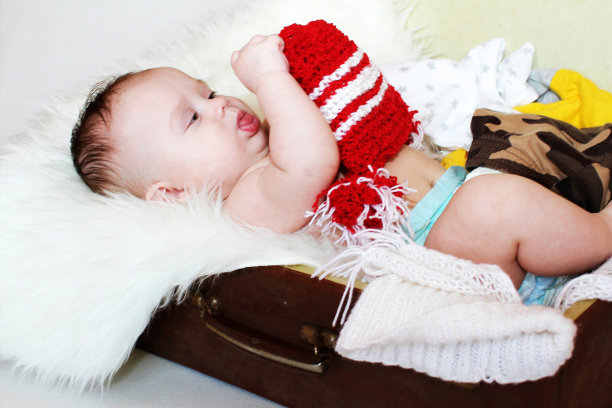 婴儿看着躺在行李箱里的红帽子图片下载