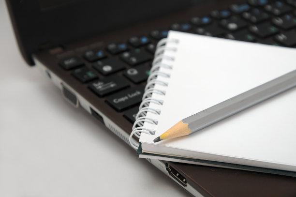 笔记本和铅笔在棕色笔记本键盘上图片下载